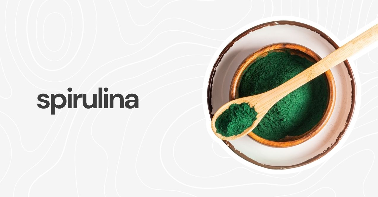 Spirulina powder in a bowl with a wooden scoop.