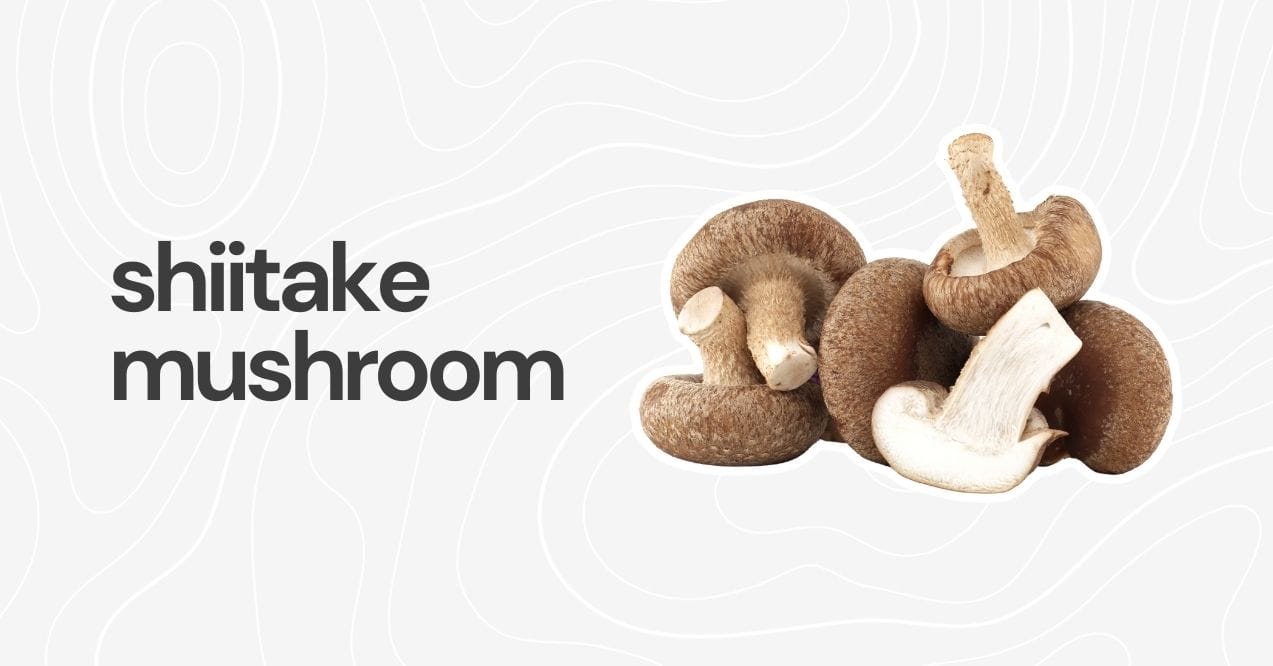 Fresh shiitake mushrooms, including one sliced, on a simple white backdrop.