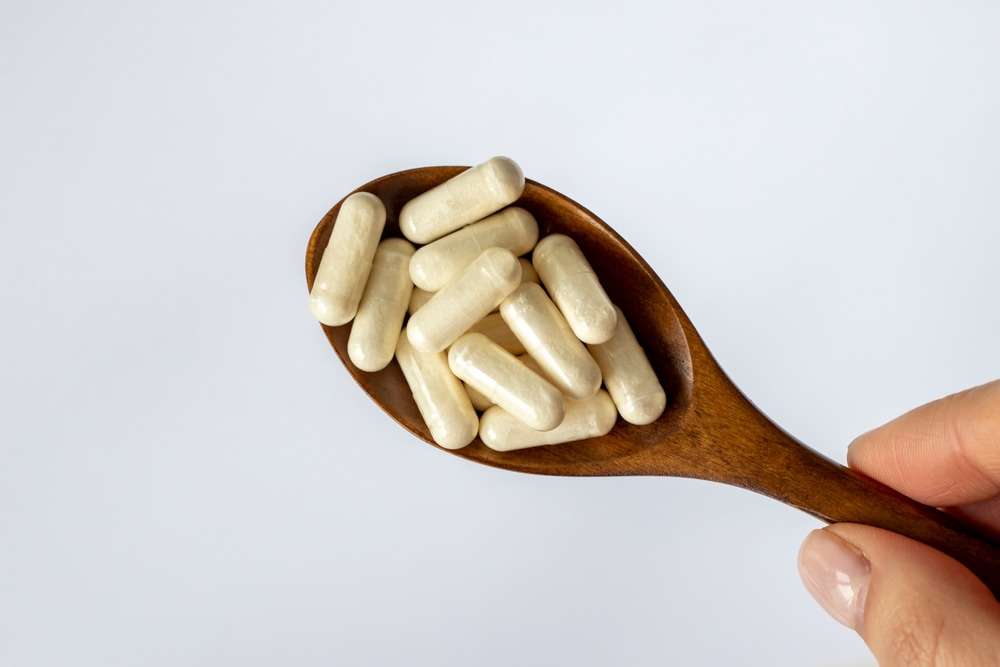 Probiotic Capsules on a Wooden Spoon