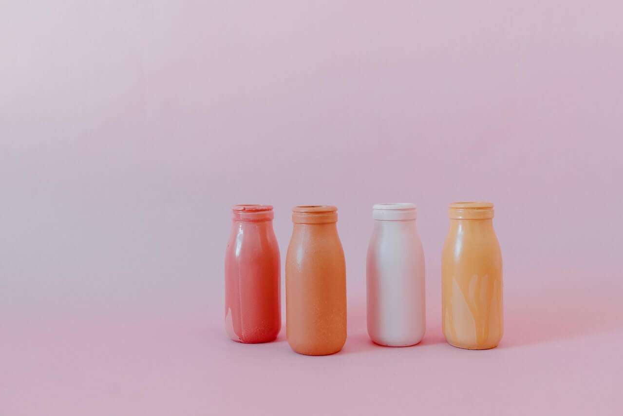 four plastic bottles in pink background