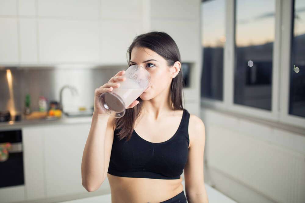 a young athletic woman drinking superfood powder drink for gut health