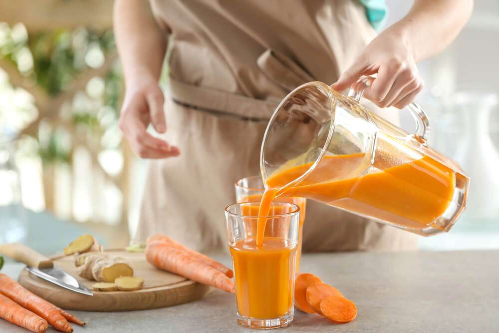 Woman filling a glass of fresh Carrot Juice