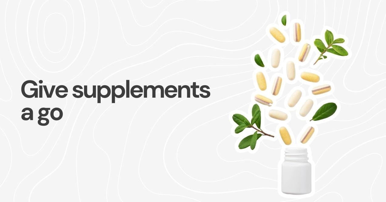 Supplement pills pouring from a bottle with green leaves.