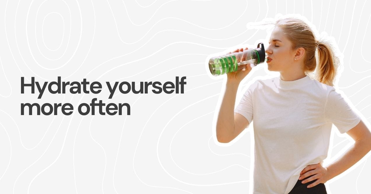 Woman drinking water from a bottle outdoors.