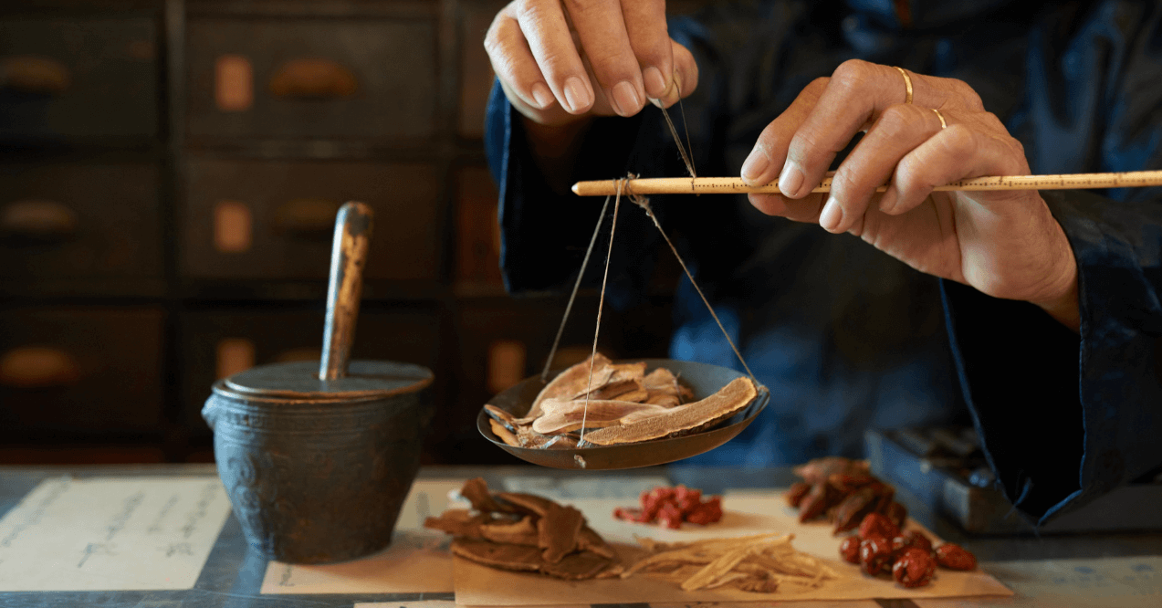 Man measuring ingredients in traditional Asian apothecary