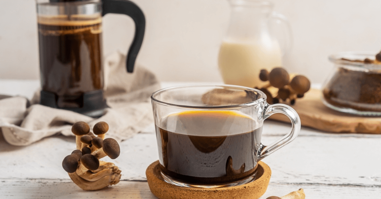 Healthy trendy coffee with mushrooms in cup, coffee pot, milk on white wooden background