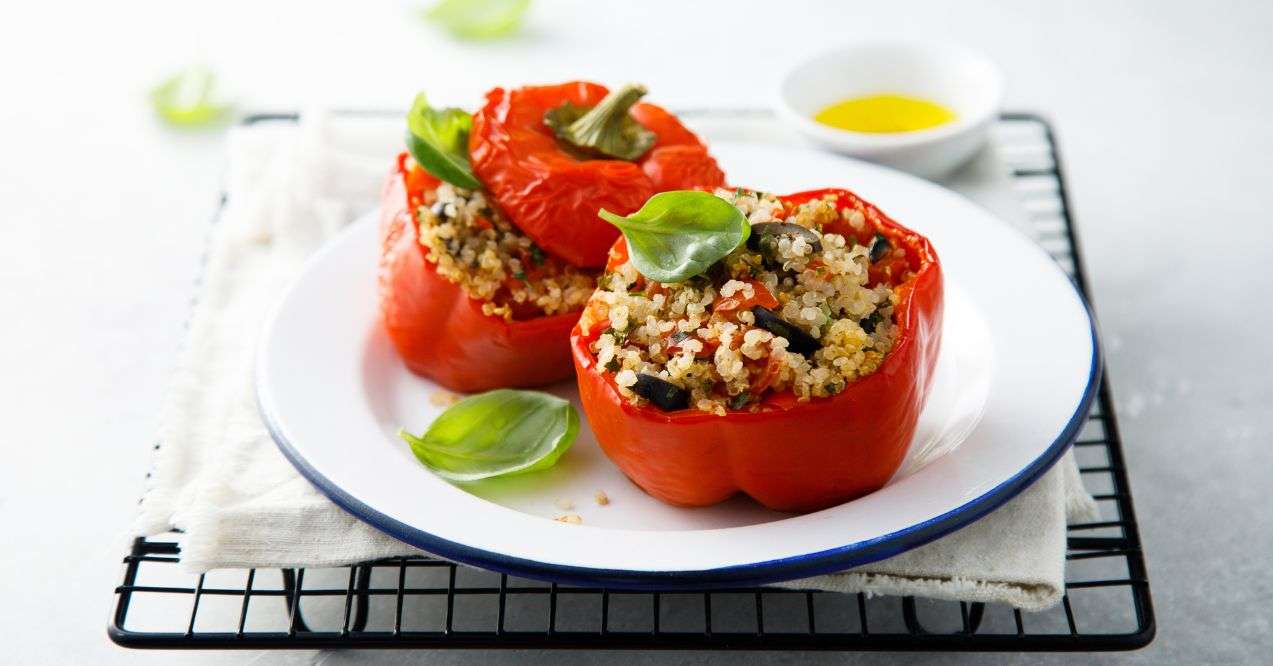 Two cooked bell pepper stuffed with quinoa on a white plate