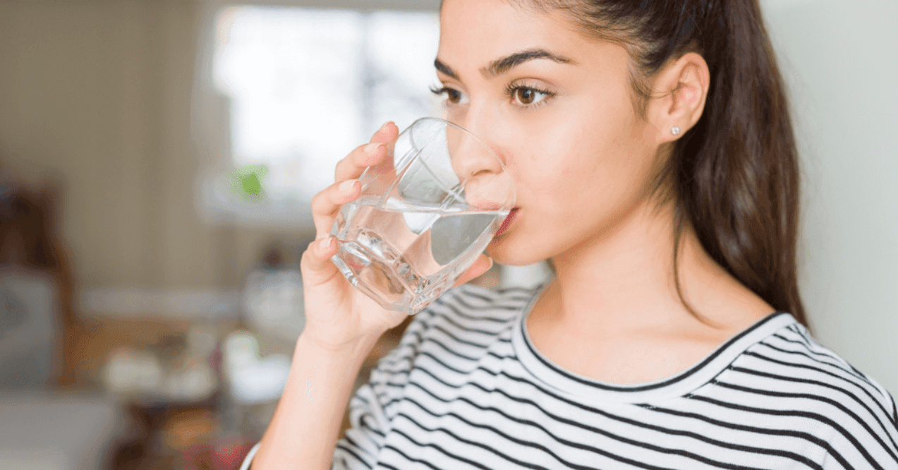 Beautiful young woman drinking a fresh glass of water at home