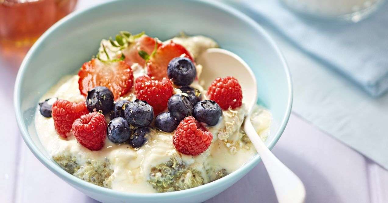 Zoomed in bowl of quinoa porridge with blueberries, strawberries and raspberries on top