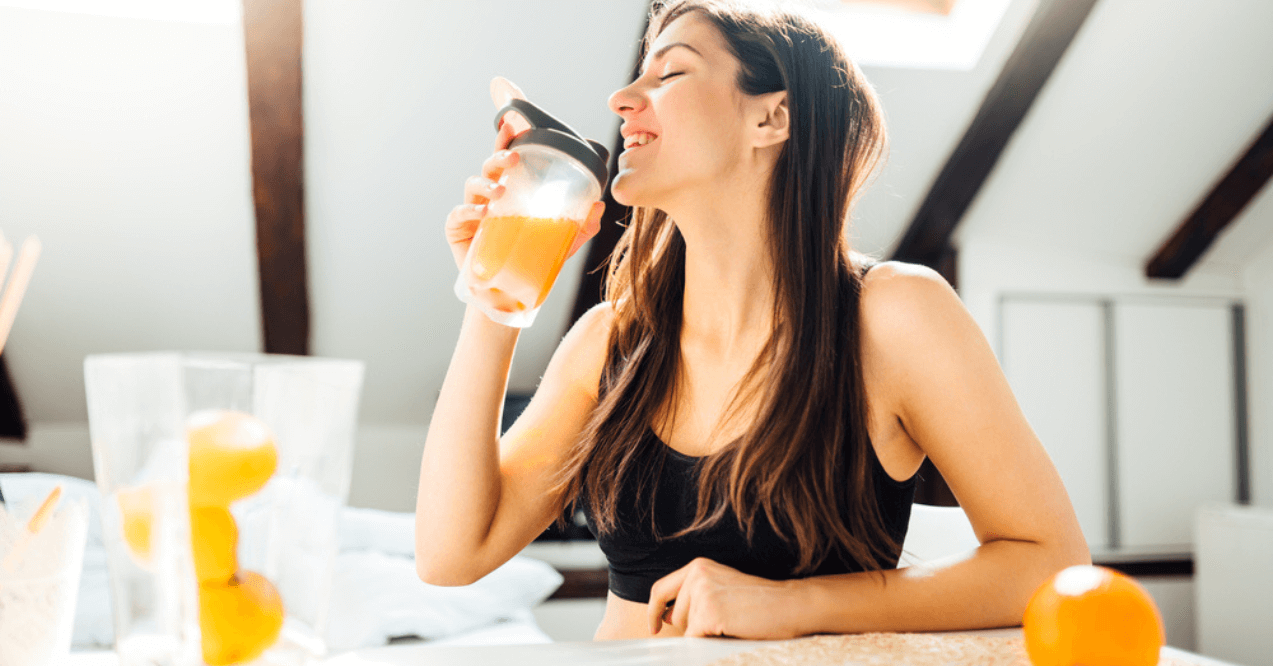 Woman at home drinking orange flavored amino acid vitamin powder