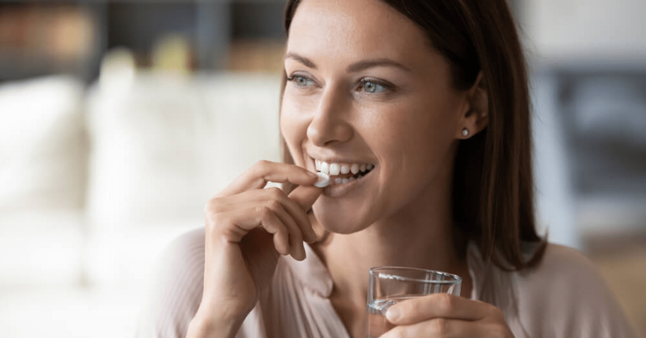 Woman taking supplements and drinking water 