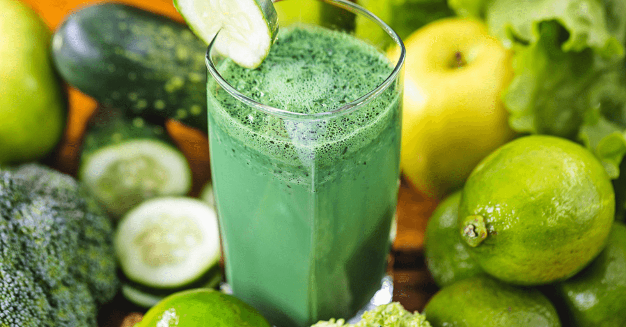 Healthy Green Smoothie with vegetables in the background