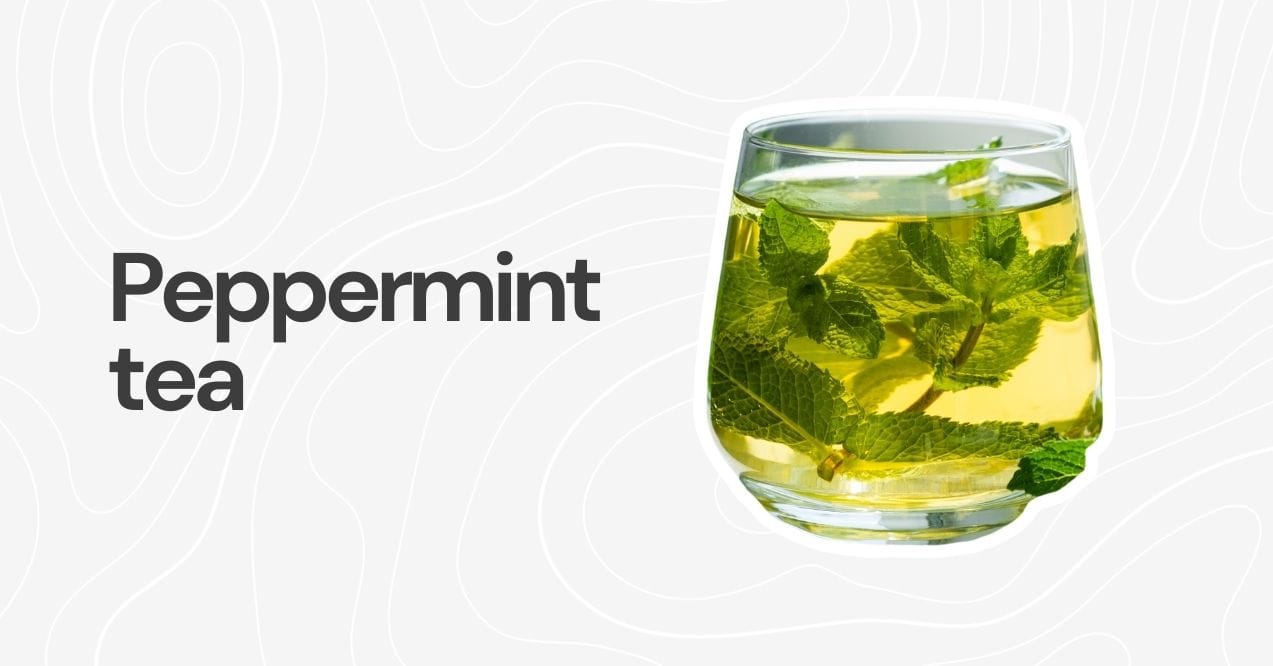 A clear glass of peppermint tea with fresh peppermint leaves.