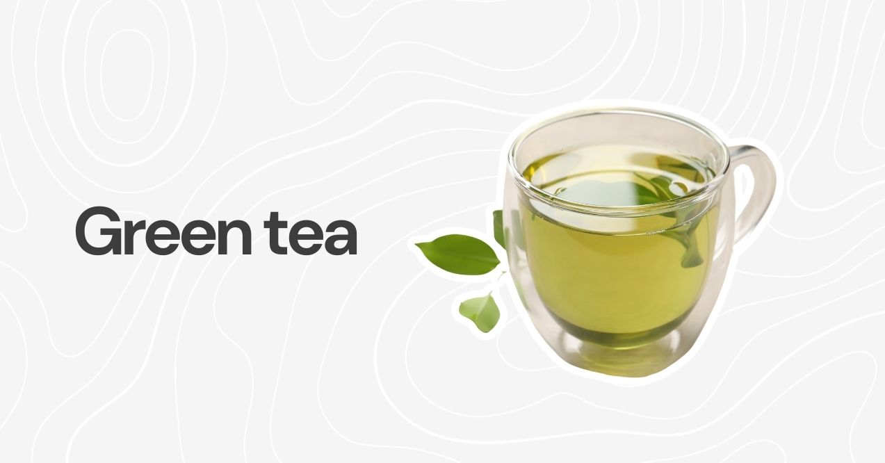 A glass cup of green tea with tea leaves on a light background