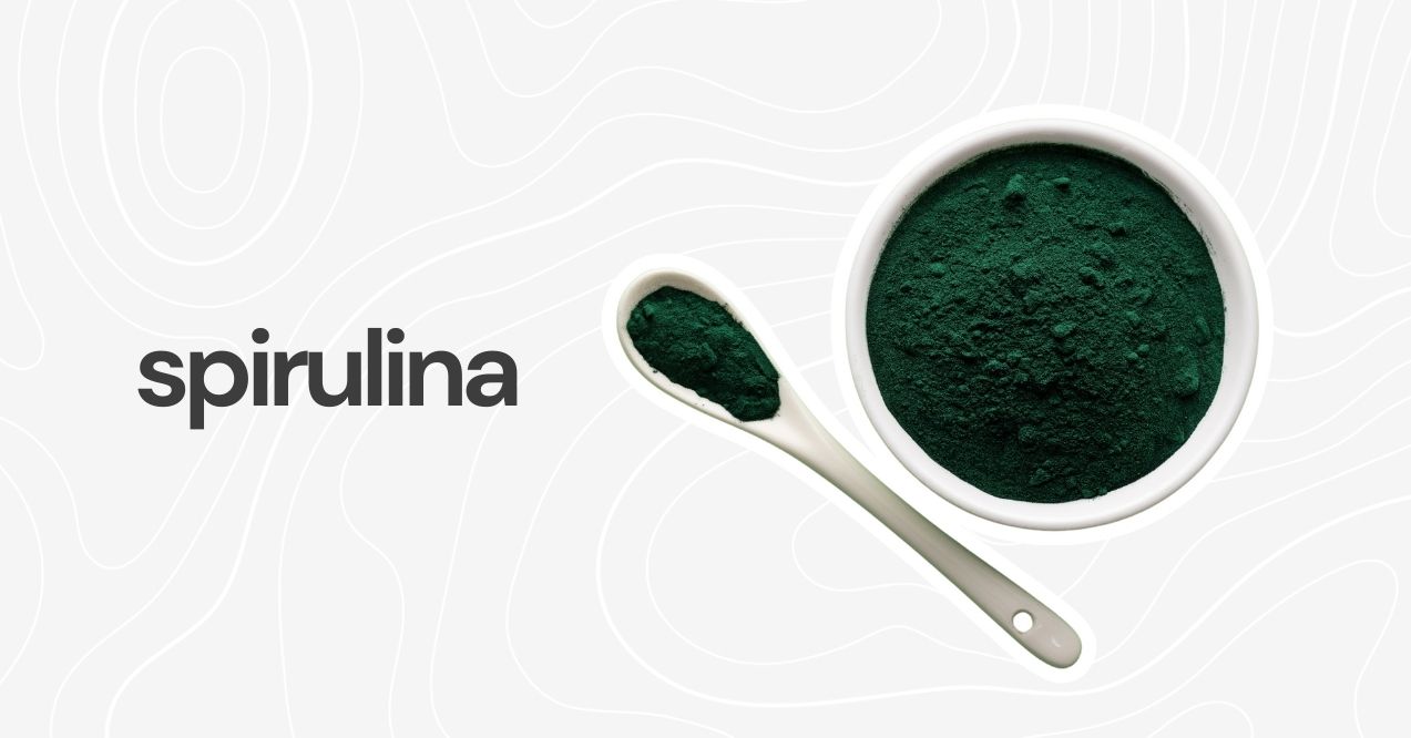 White bowl and spoon filled with green spirulina powder.