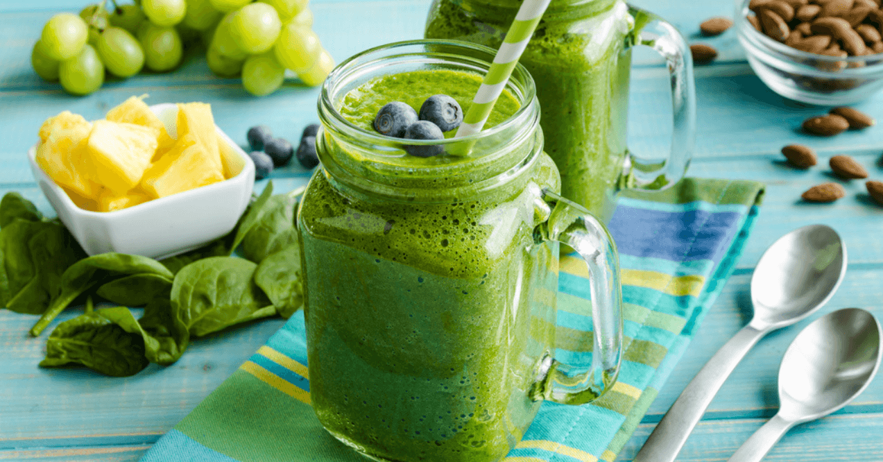 Green Smoothie with spoons and grapes in the background