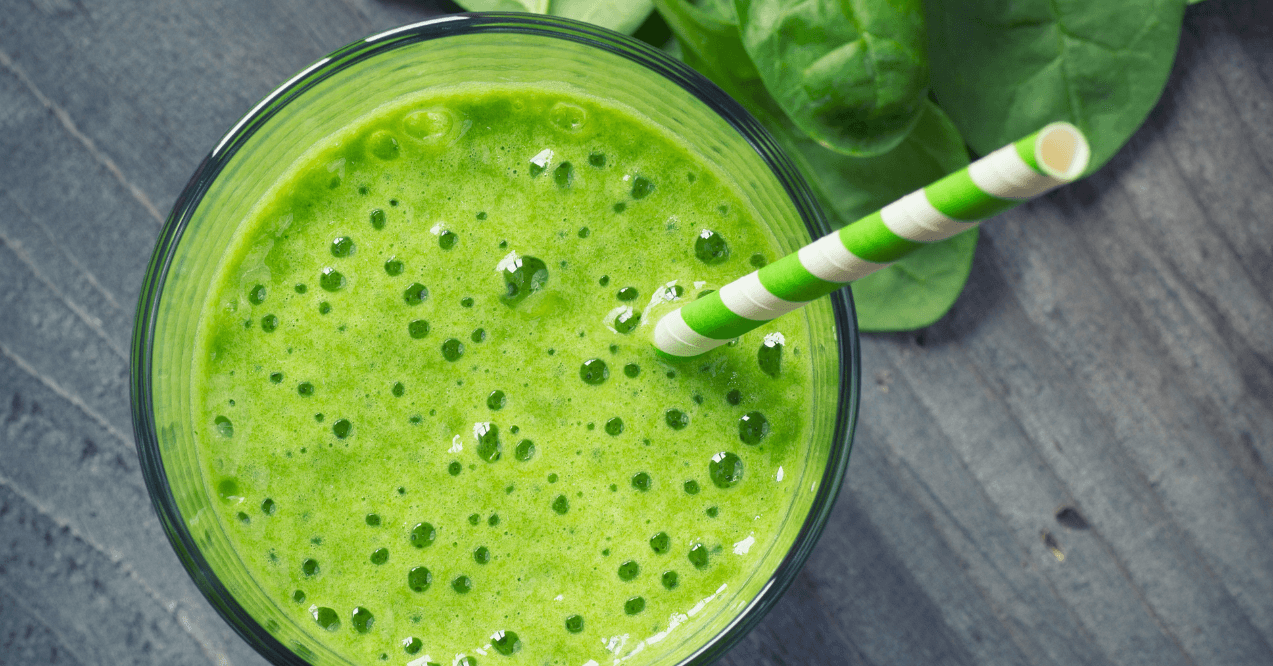 Spinach smoothie with a green and white straw