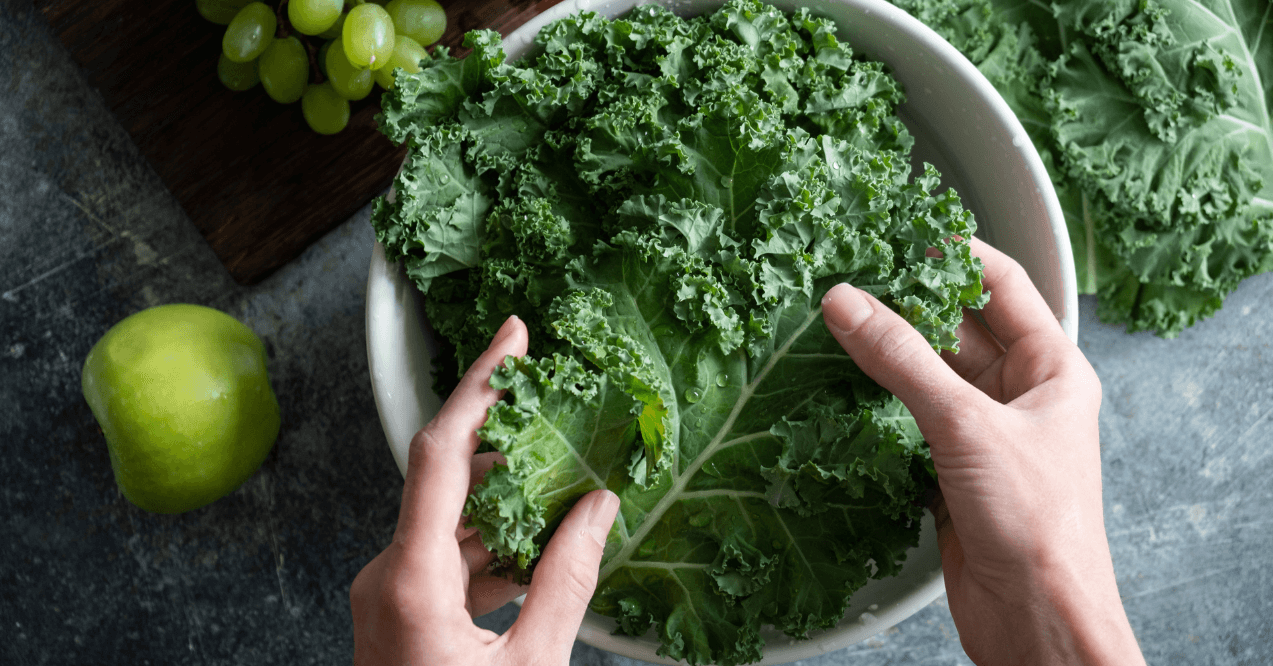 Female hands washing kale cabbage in bowl of water. Cooking healthy organic home grown vegan food, top view