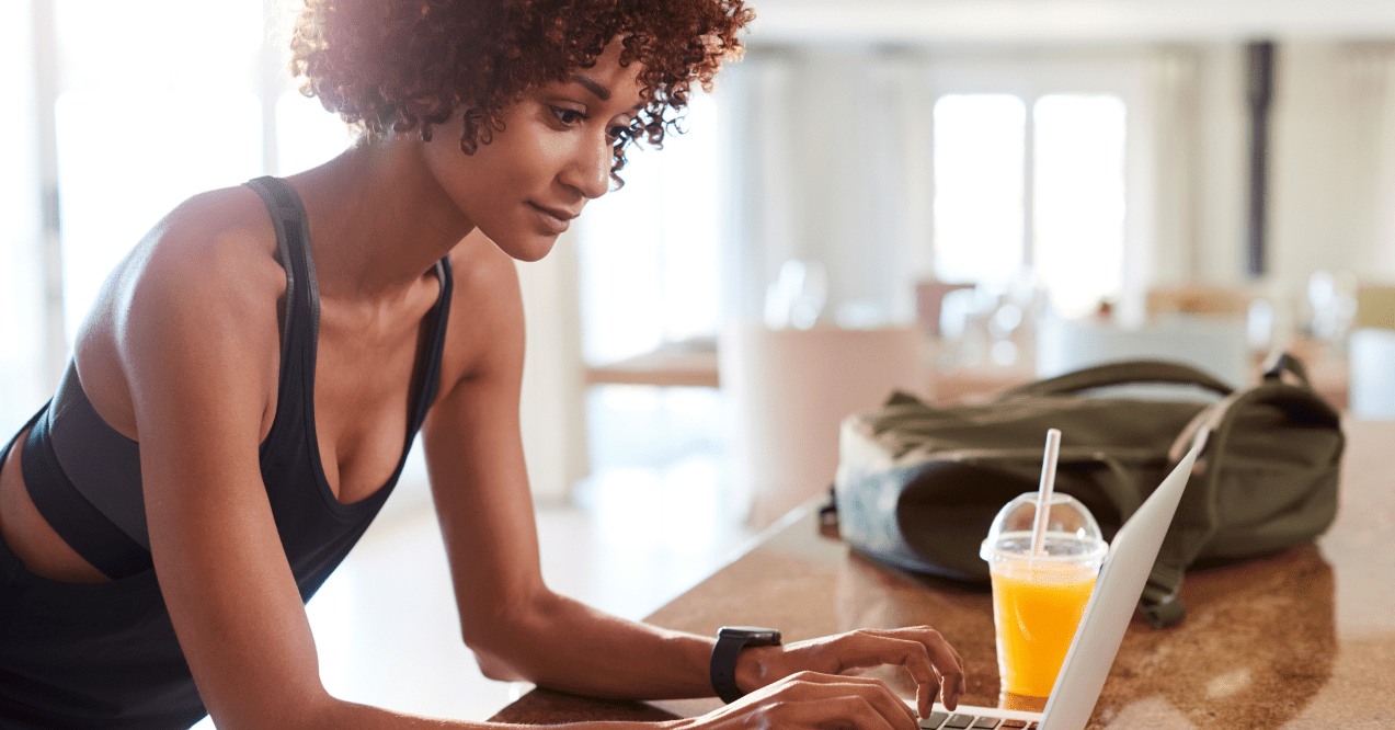 Millennial African American woman scrolling on her laptop after workout, side view