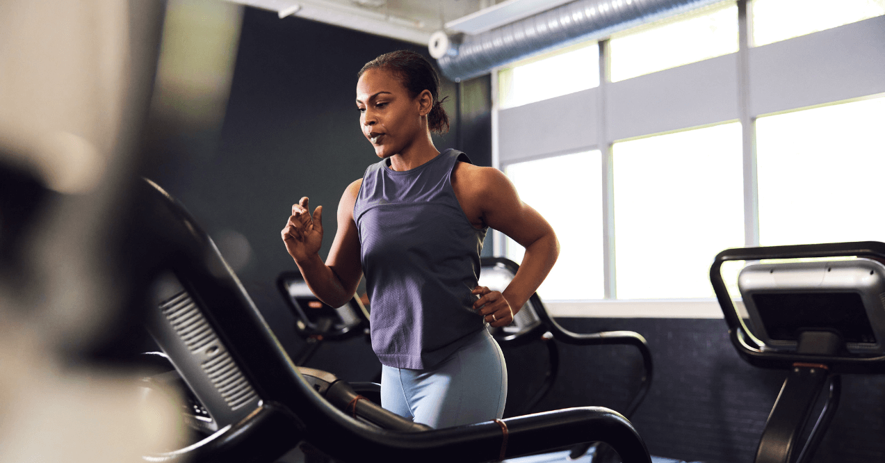 Fit young woman in sportswear running on a treadmill during a workout at the gym