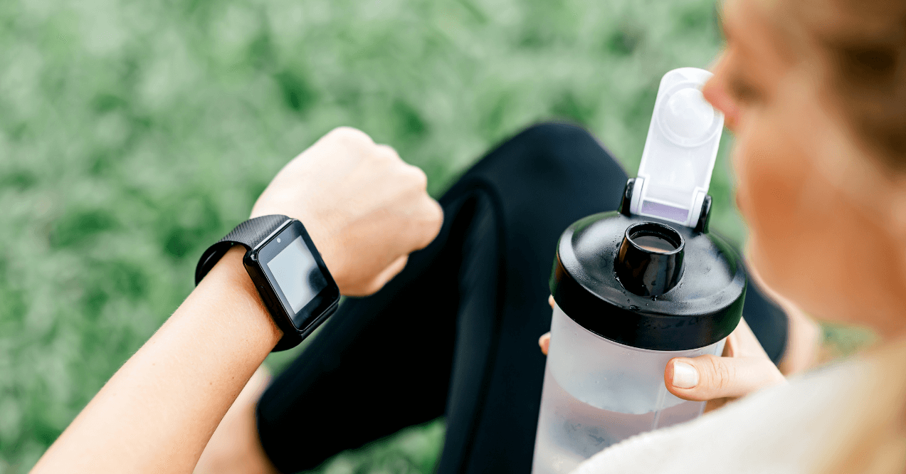 Woman taking pre-workout and looking at her watch