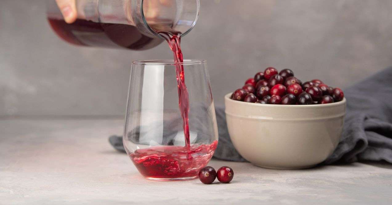 Glass with healthy cranberry juice on light gray background.