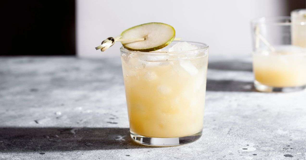 A short glass of refreshing pear soda water mocktail or cocktail on gray concrete background. Non alcoholic summer drink.