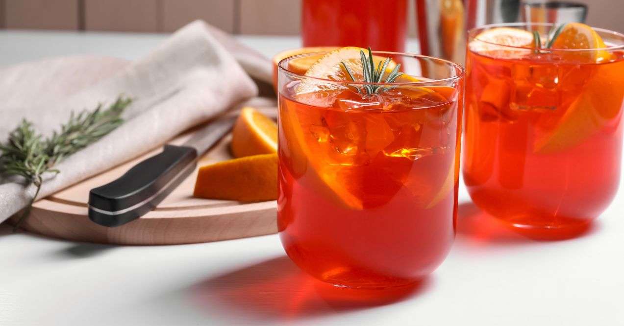 Aperol spritz cocktail, rosemary and orange slices on white wooden table