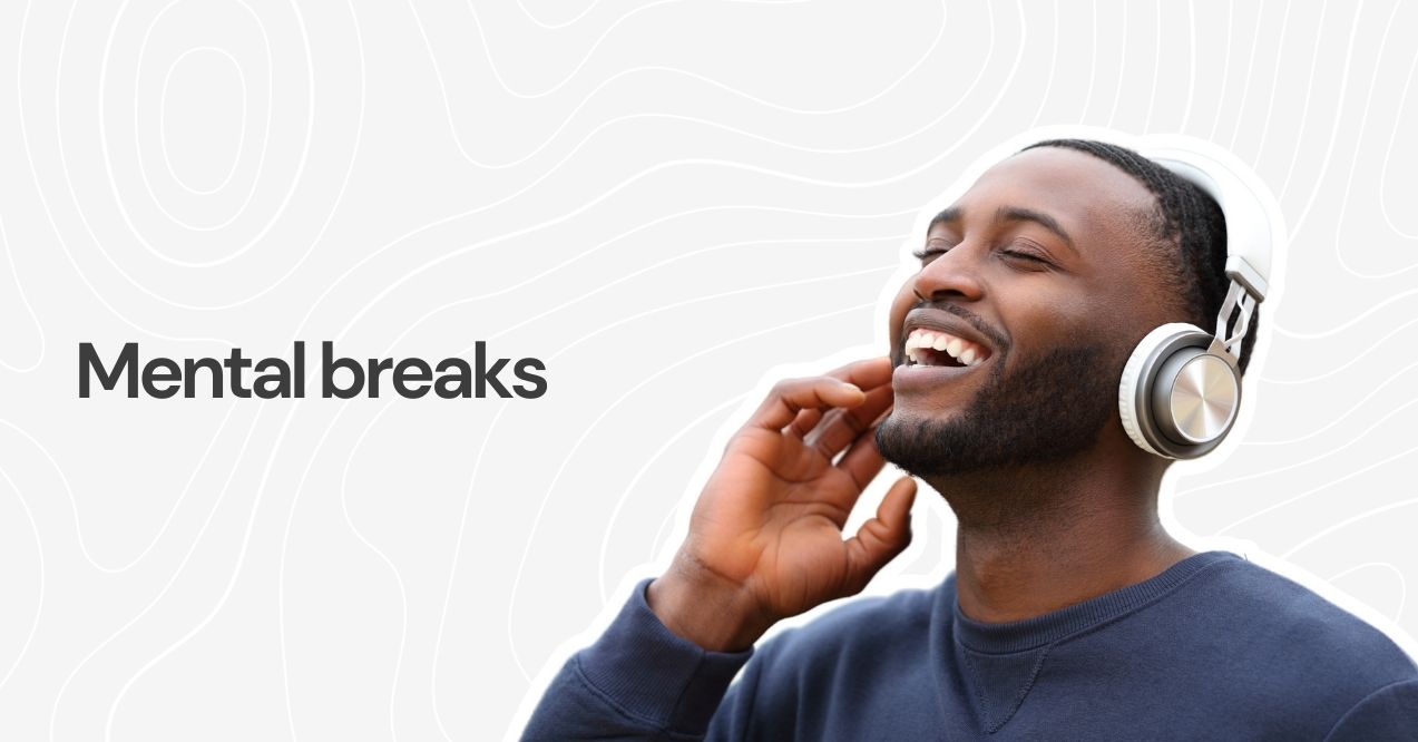 Smiling man listening to music with headphones, enjoying a mental break.