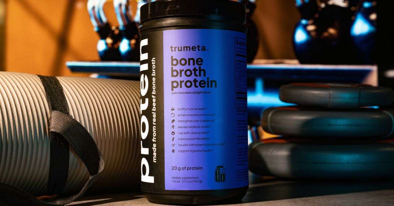 purple trumeta bone broth product visual in a gym background. zoomed in