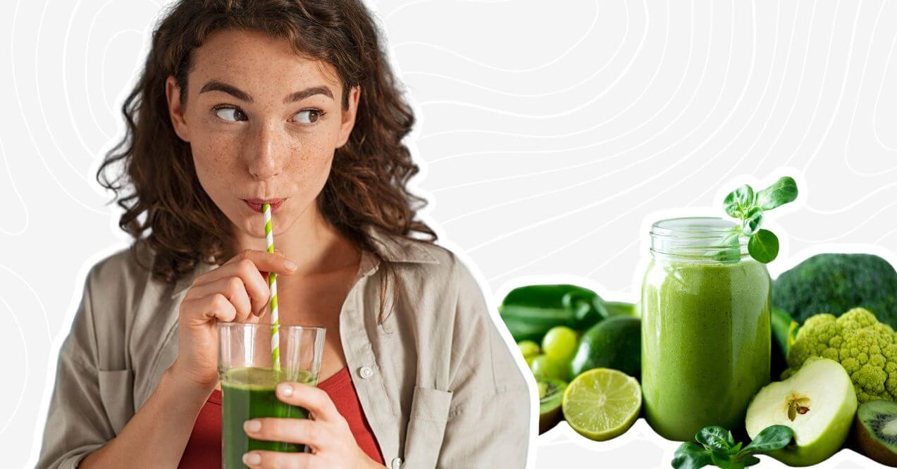 Young woman drinking a green smoothie with a straw; ingredients for the best smoothies for gut health in the background.