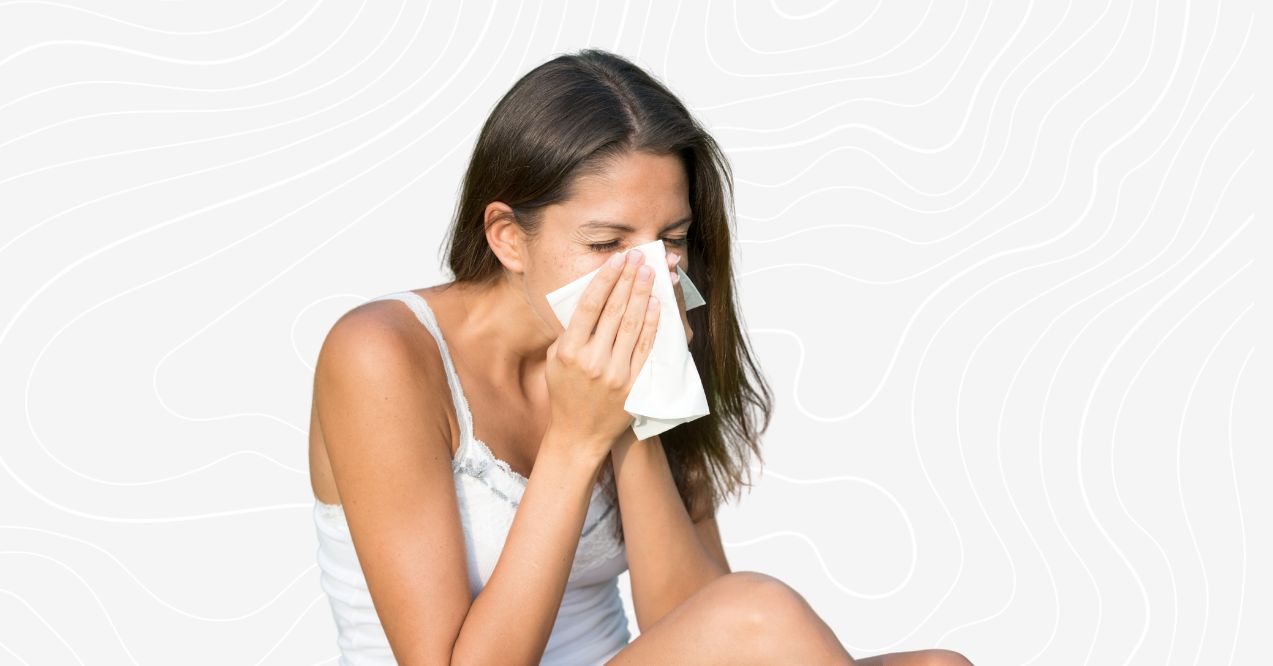 A female blowing her nose into a napkin due to allergy on the grey custom background