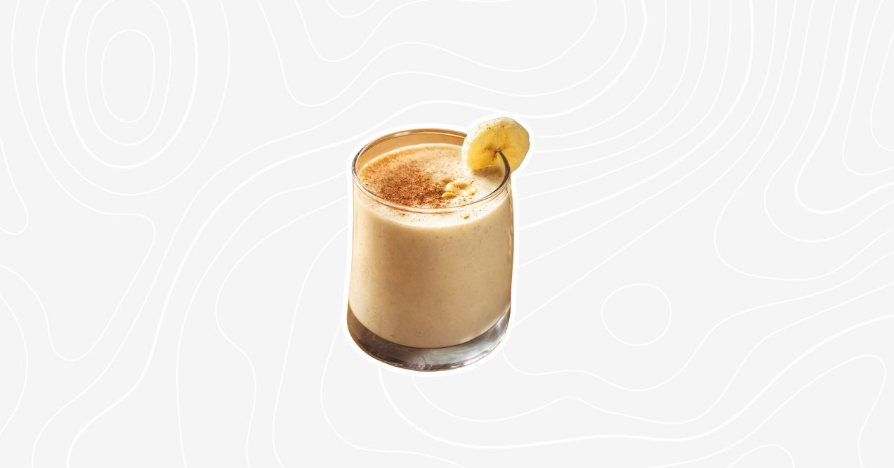 A creamy banana coffee smoothie in a glass garnished with a banana slice and a sprinkle of cinnamon.