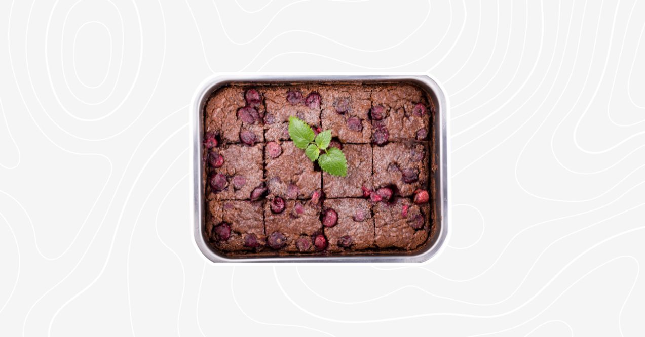 A tray of cherry coffee cake squares topped with cherries and garnished with a sprig of mint.