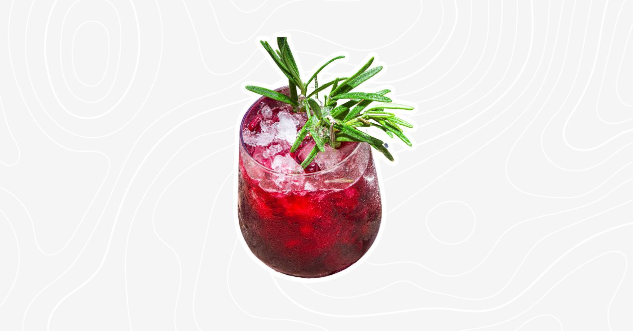 A ginger beer mocktail with ice and a sprig of rosemary for garnish.