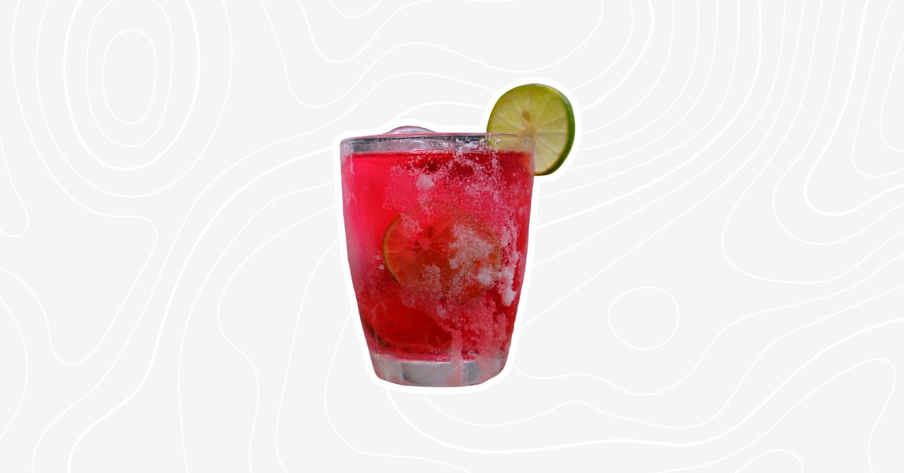 A bright pink kiddie mocktail with lime slices, served with ice.