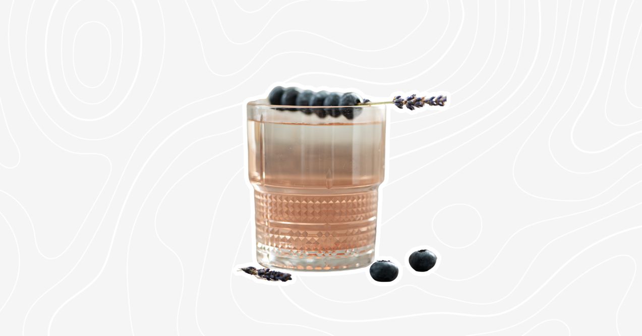 A lavender mocktail garnished with blueberries and a sprig of lavender.