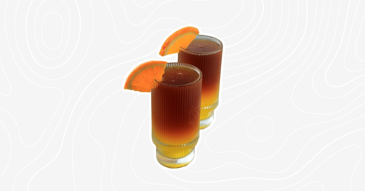 A duo of old-fashioned mocktails garnished with orange slices.