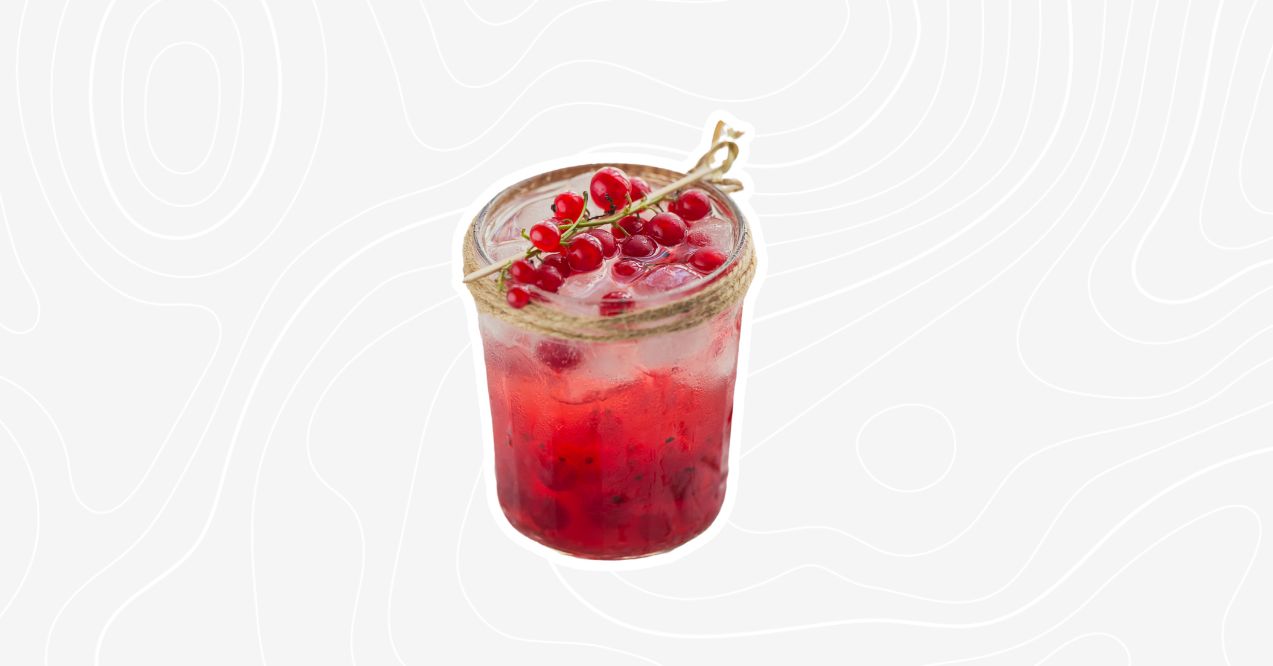 An organic red mocktail garnished with red currants and ice.