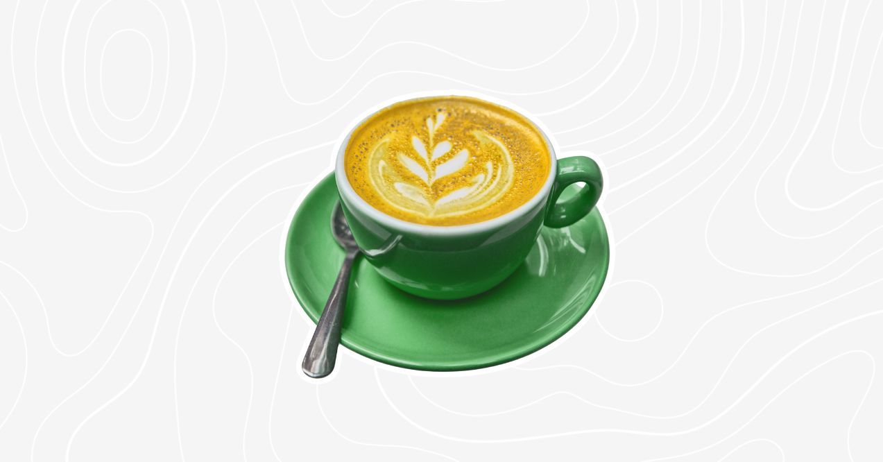 A cup of turmeric mushroom coffee with latte art served in a bright green cup and saucer.