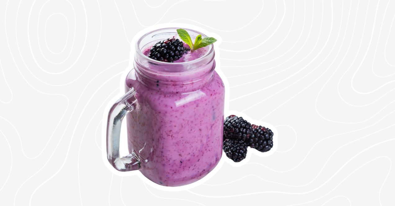 Purple bone broth smoothie with blackberries and a mint garnish in a mason jar.