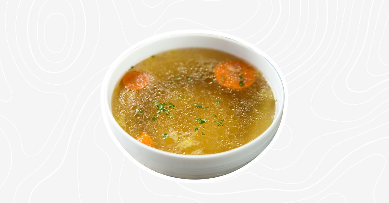 Bowl of classic chicken bone broth soup with carrots and herbs.