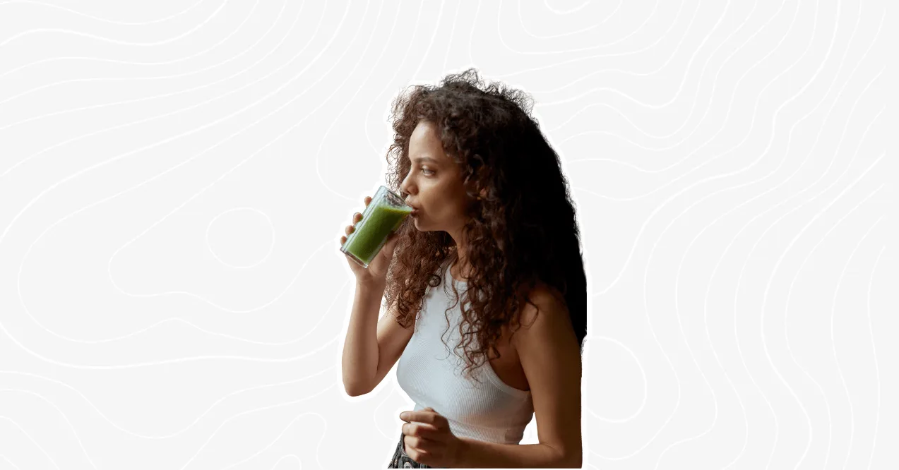 curly haired woman drinking a green smoothie