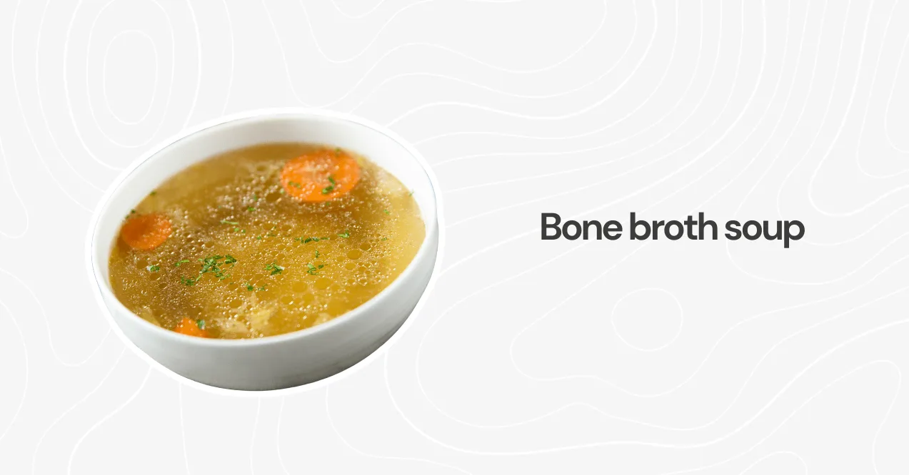 A bowl of warm bone broth soup with carrots and parsley, packed with collagen and nutrients for gut health.