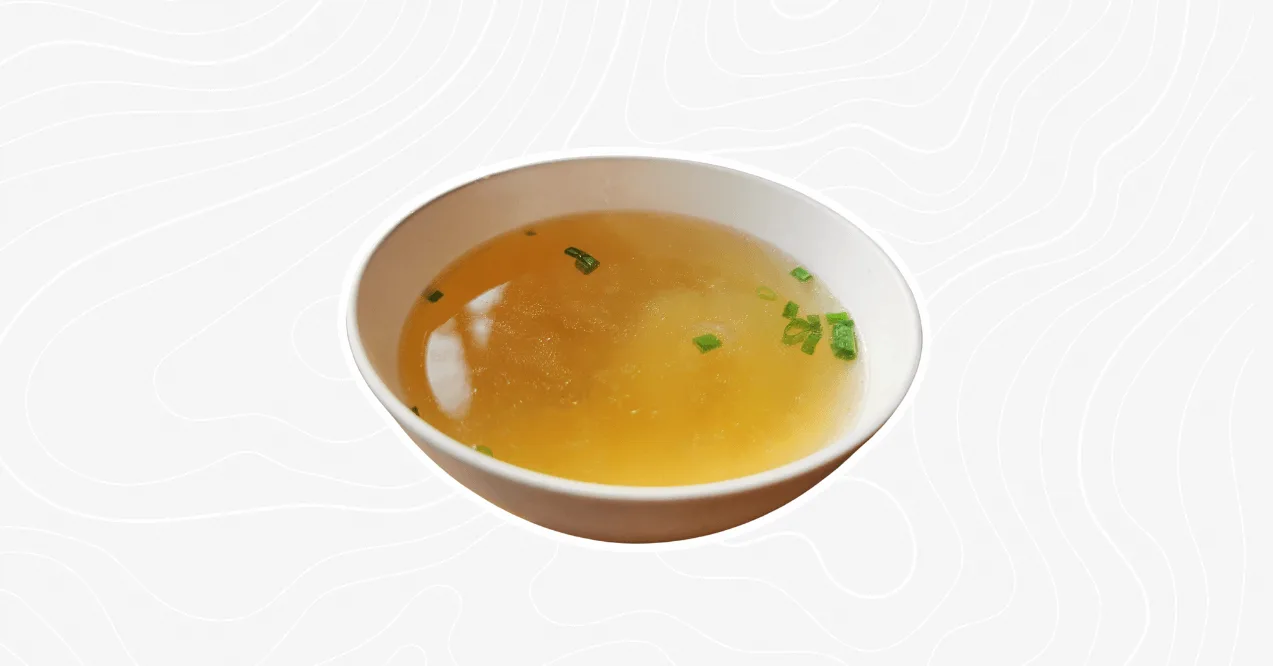 A bowl of warm bone broth soup garnished with fresh green onions, rich in collagen and nutrients for gut health and immunity support.