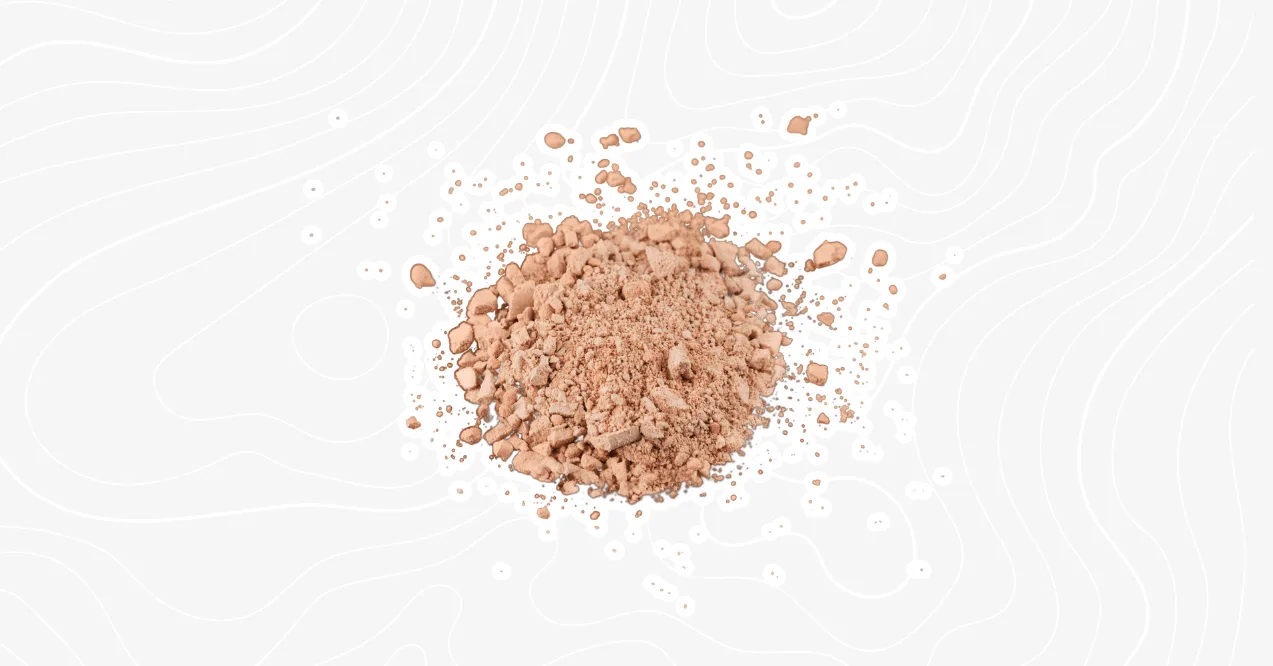A pile of chocolate protein powder scattered on a white background with a subtle textured design.