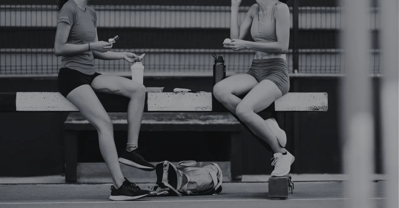 Two athlete women snacking before the training session. Black and white image.